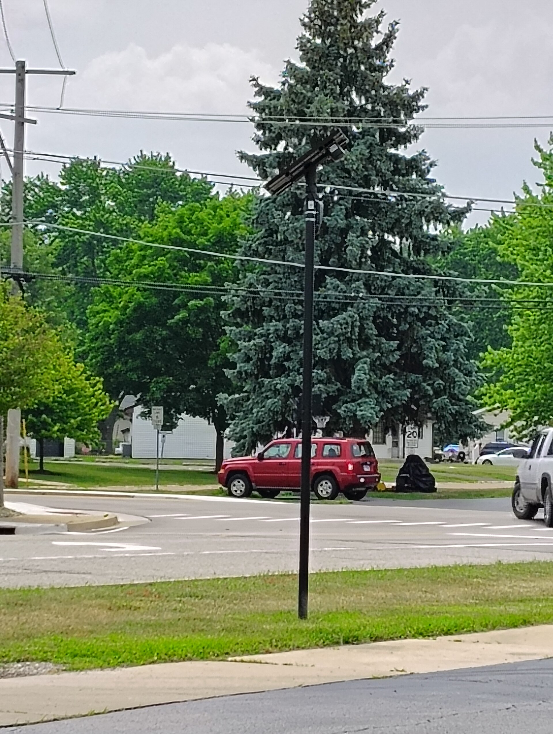 A discreet solar-powered Flock camera beside a suburban intersection