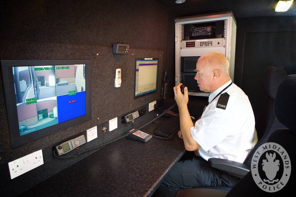 Police officer monitoring automated number plate recognition screens inside a specialist van