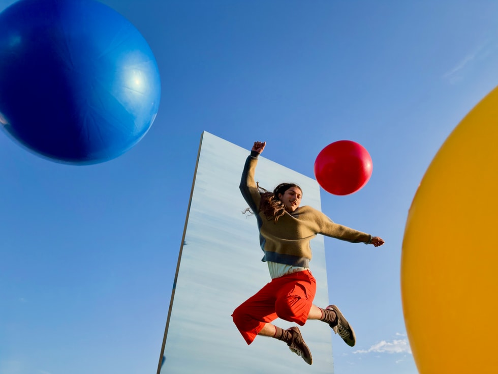 An outdoor action photograph of a person jumping among colorful inflatable balls